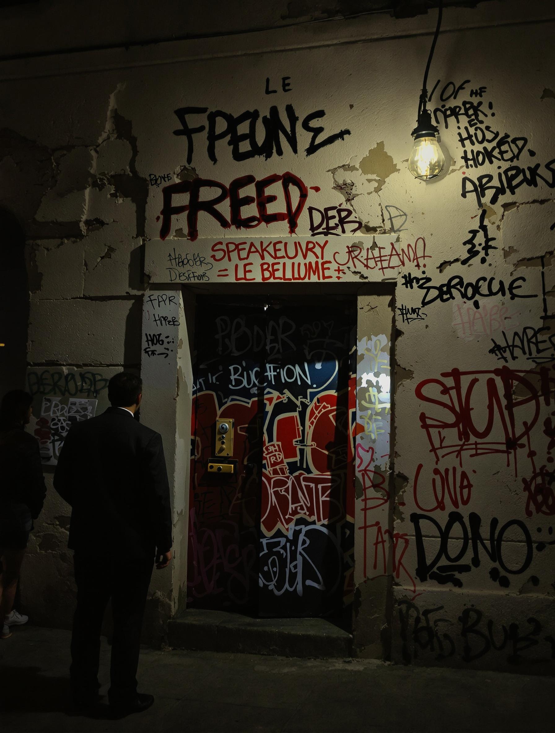 Entrée cachée d’un speakeasy à Budapest, dissimulée derrière un porche avec graffitis