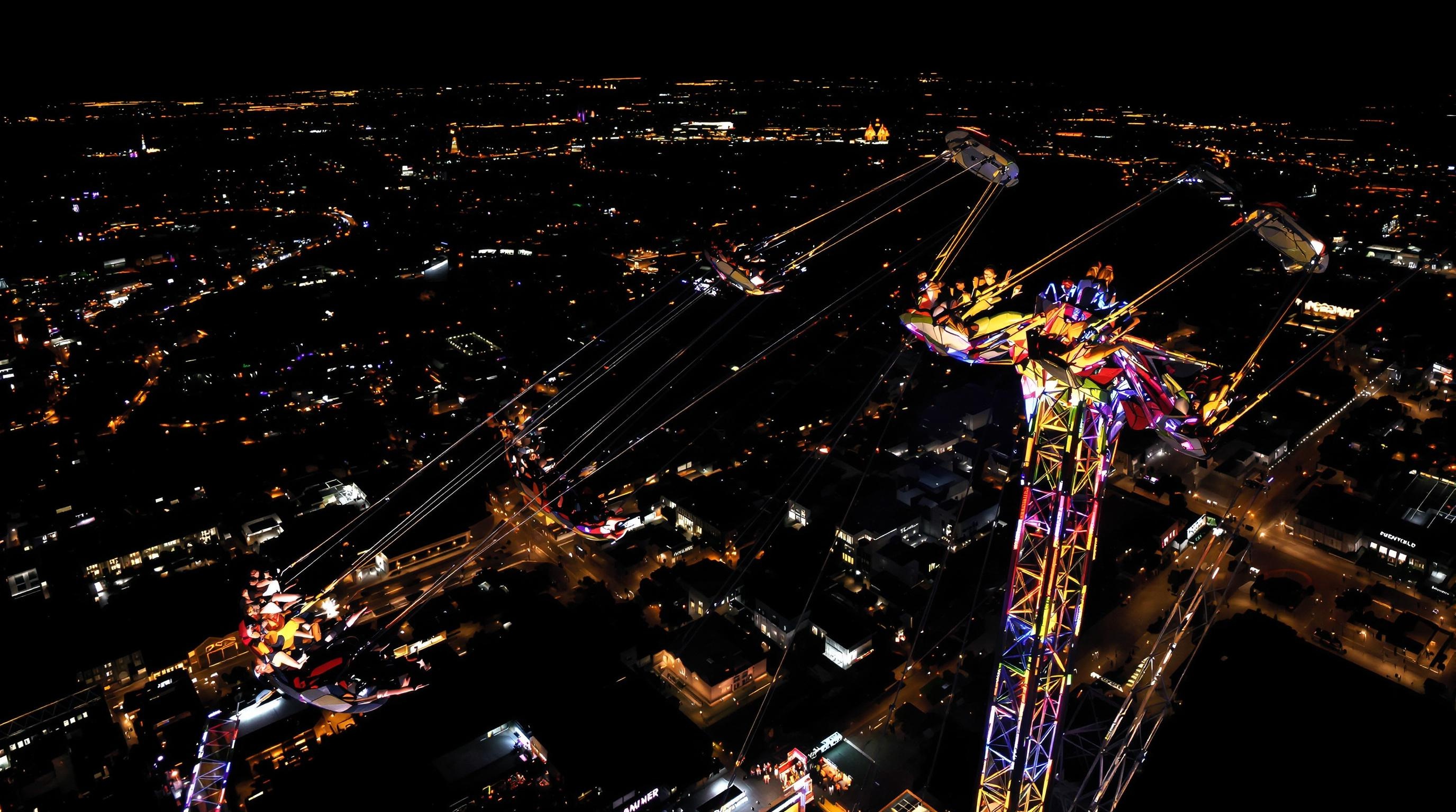 Vue aérienne nocturne du Star Flyer à Tivoli Gardens, passagers hilares flottant au-dessus de Copenhague